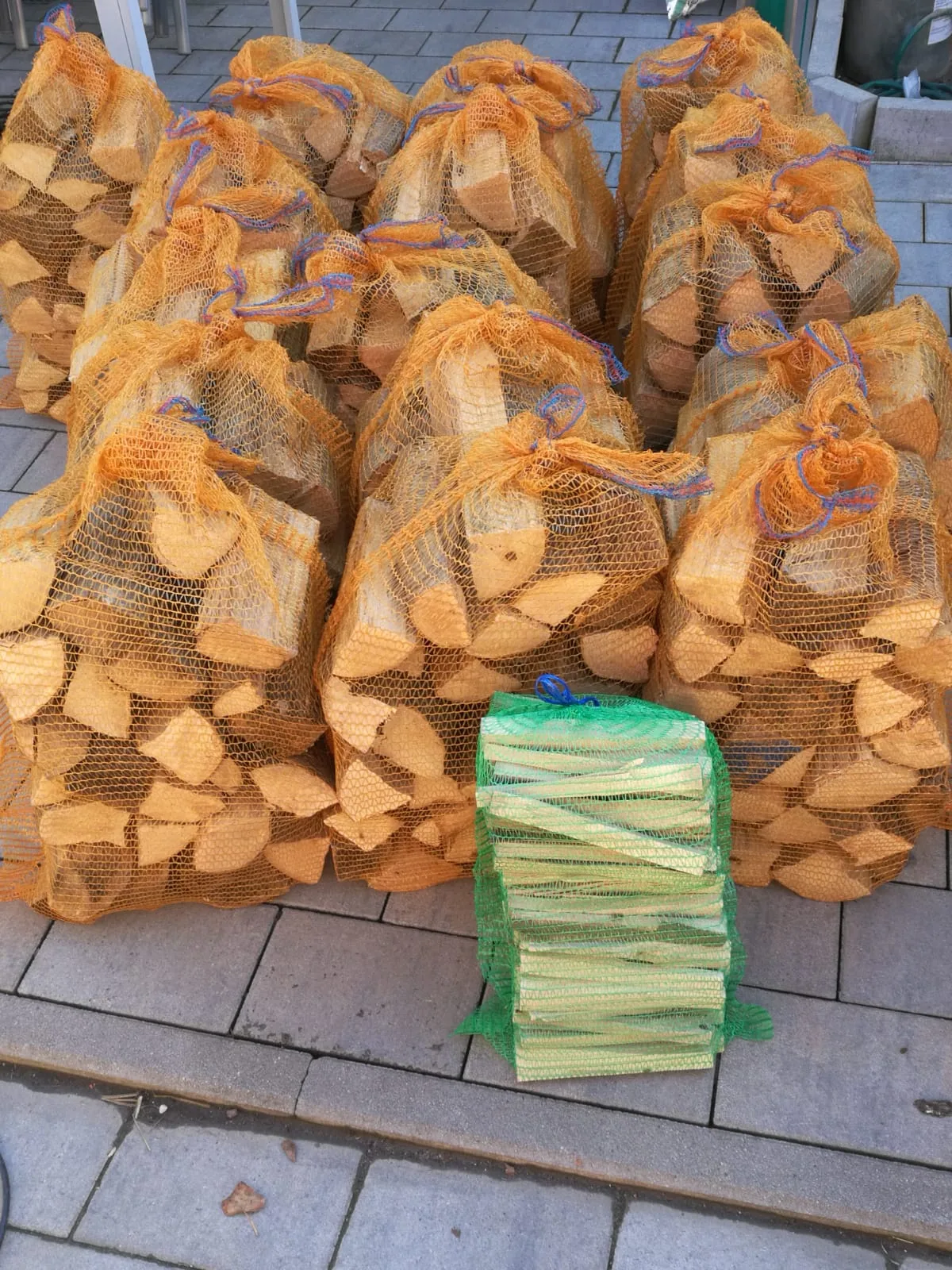 Brennholz im Netzsack und Anzündholz-Bündel